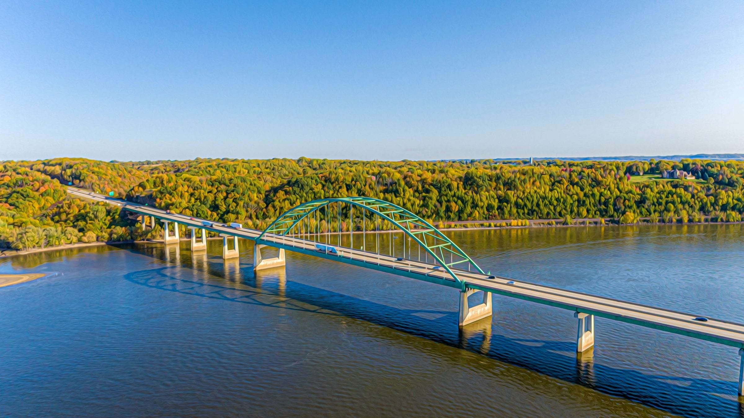 Towing East Peoria IL: highway bridge over a wide river with wooded bluffs in autumn, the kind of road our trucks cover around East Peoria